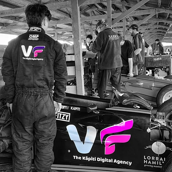 Yoshi Comeskey in a VF race suit beside his Formula First car in the pits